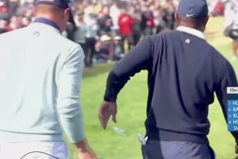 Justin Thomas throws away a tampon after being handed it by Tiger Woods
