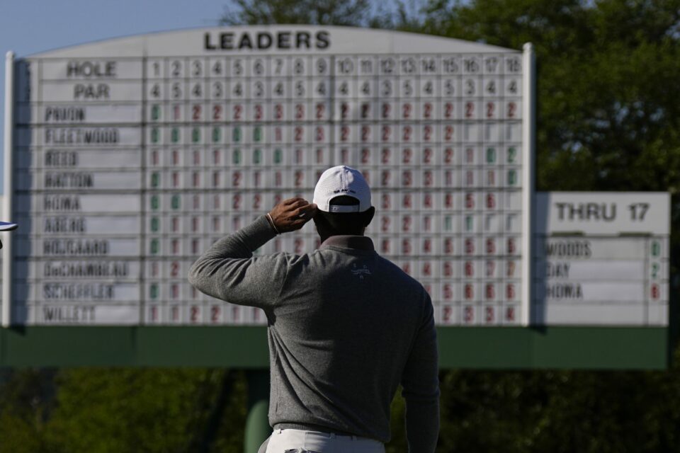Woods looks at the leader board on the 18th hole as he eyes a sixth title