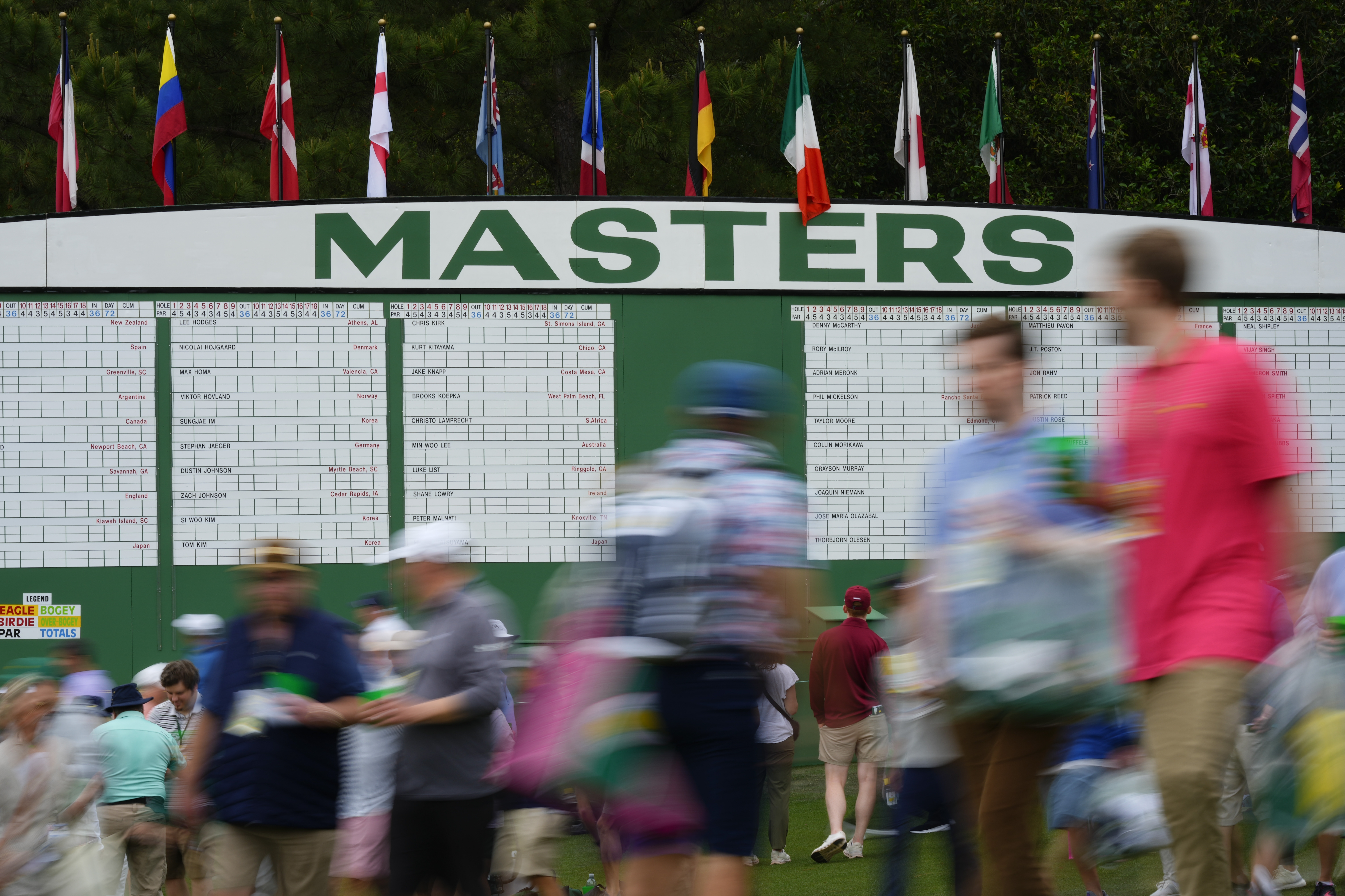Patrons walk past the main scoreboard during a practice round at the Masters (AP Photo/Matt Slocum)