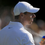 Rory McIlroy sprays on sunscreen on day two of the US Open